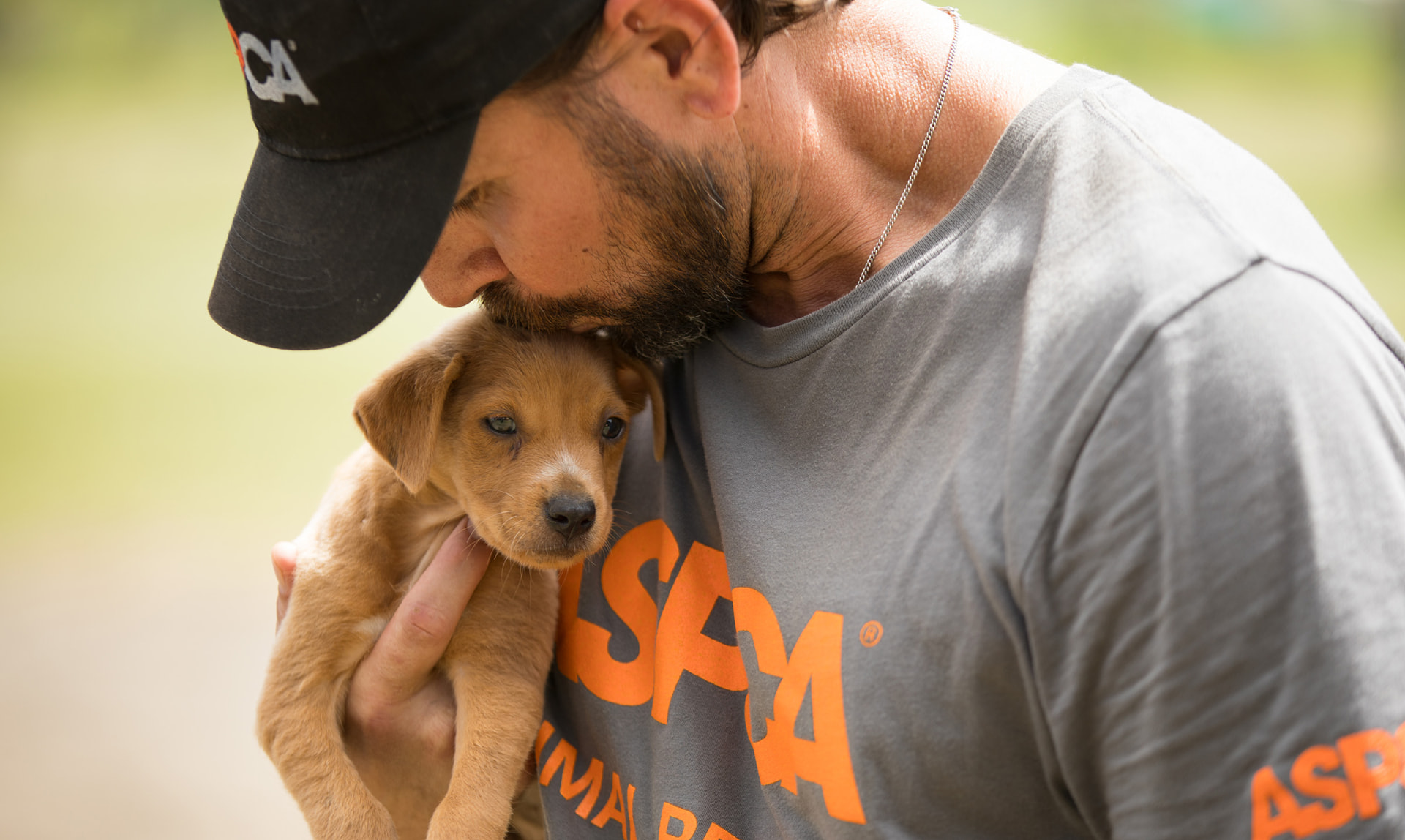 ASPCA caregiver in an ASPCA shirt holding a rescued puppy