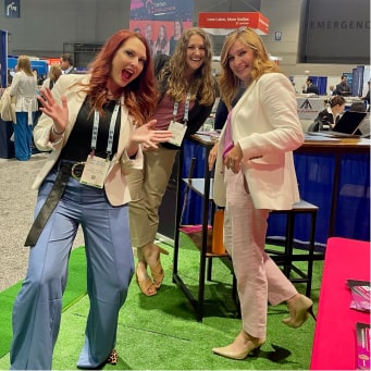 Three of our Straight Consulting team members smiling at a conference
