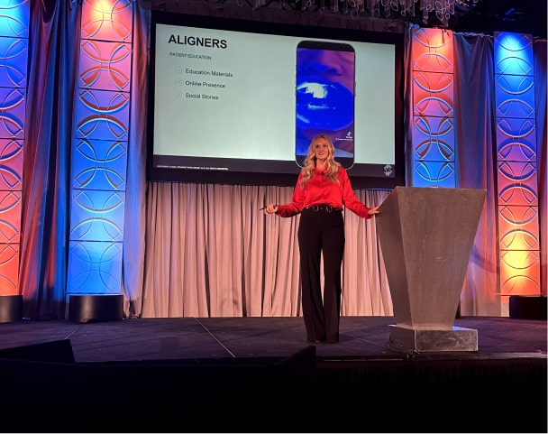 Revitalize Your Conference: Add Engaging, Actionable Content to Boost Case Acceptance and Practice Performance Alisha on stage giving a lecture